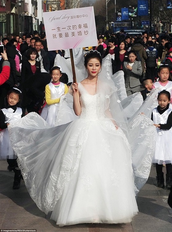 بالفيديو والصور.. «موديل» تسير بفستان طوله 100 متر في شوارع الصين