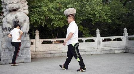 بالصور صيني يحمل حجراً على رأسه ليخسر الوزن الزائد