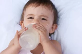 حليب النمو للأطفال بعد السنة: هل يكفي الحليب البقري وحده لبناء مناعة قوية ونمو متوازن؟ 17 baby portrait drinking milk nutrition liquid food relax bed home girl toddler formula health child development 303473145
